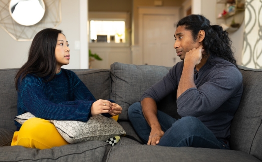 Serious, straight couple talking together on a couch