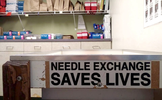 Local clinic with "needle exchange saves lives" sticker on the side of the table