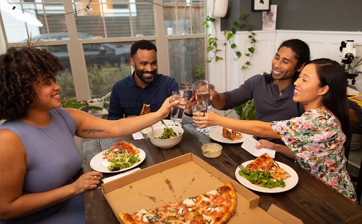 Group of friends eating dinner and cheering with waters