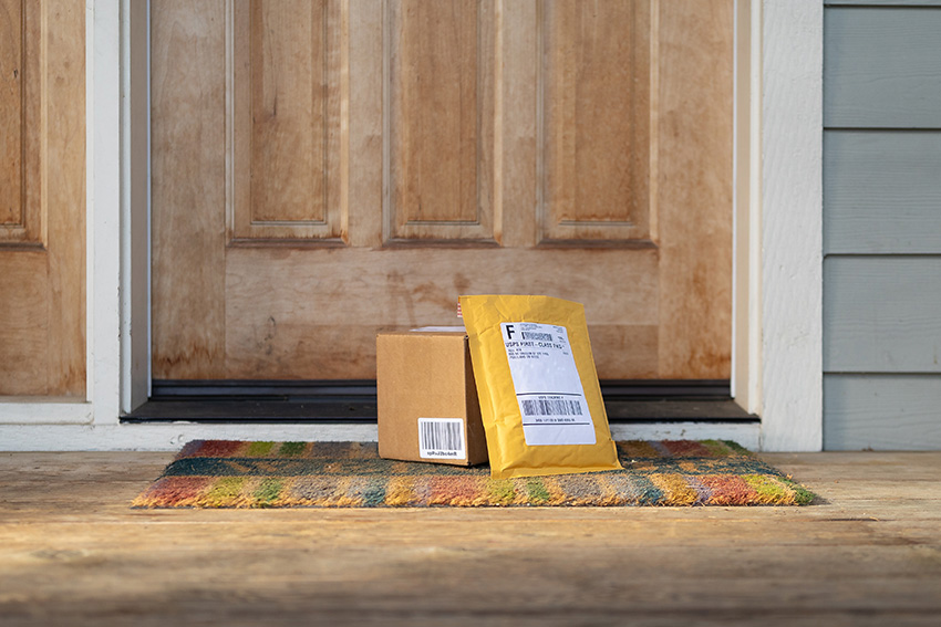 Two packages sitting on the welcome mat by a front door of a home
